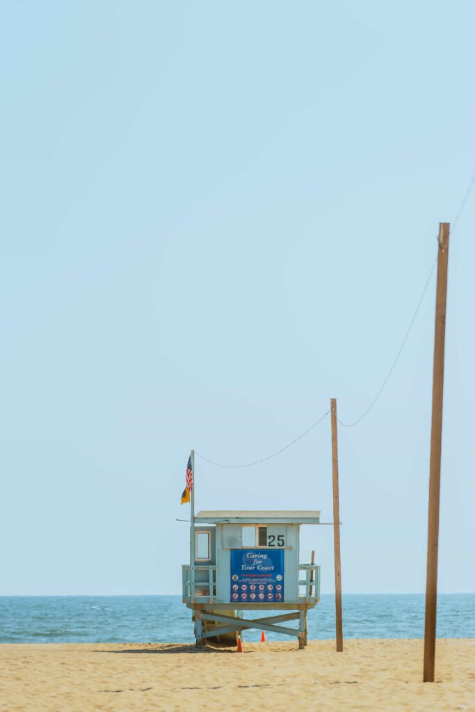 Ett livräddartorn i trä med en amerikansk flagga på en sandstrand med klarblått vatten.